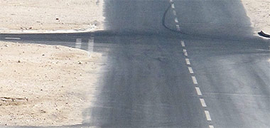 Wind driven sand and dust encroaching onto the tarmac of a suburban Doha road